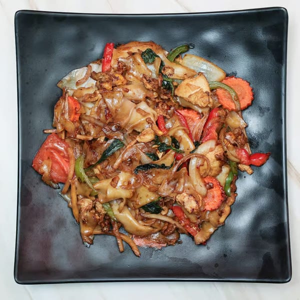 Close-up of Krungthep Thai and Pho's Pad See Ew with wide noodles, chicken, and vegetables.