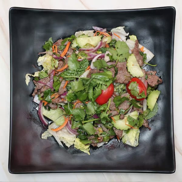 Top-down view of a Thai beef salad with red onions, cilantro, mint, and red chilies.